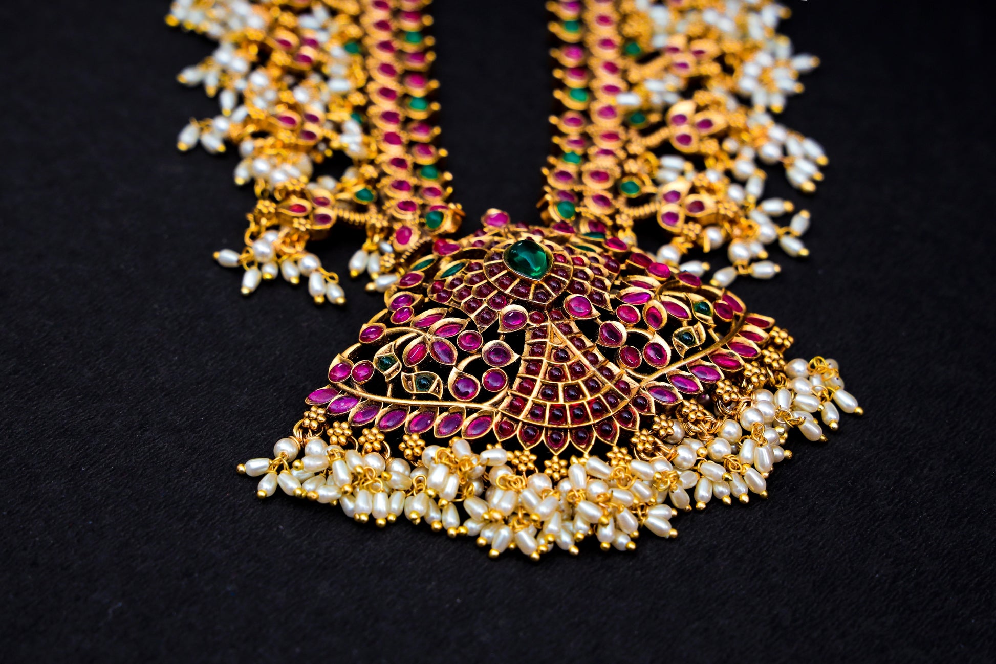 Introducing Raani's Hyderabadi Jadau Necklace Set, a rich gold plated Hyderabadi Jadau creation that embodies tradition and opulence. This exquisite set features delicate rice grain pearls and vibrant navratan stone work, meticulously arranged to capture the essence of Hyderabadi craftsmanship.