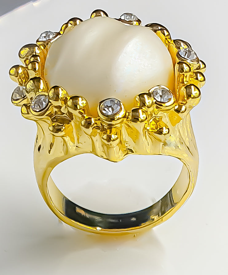 Presenting Raani's Luminous Pearl Ring, a rich gold plated faux baroque pearl statement ring that embodies classic elegance. This exquisite ring features a lustrous faux pearl in baroque style, accented by sparkling cubic zirconia on a gold-tone metal band. Its design offers a perfect blend of sophistication and glamour, suitable for both casual and dressier looks.