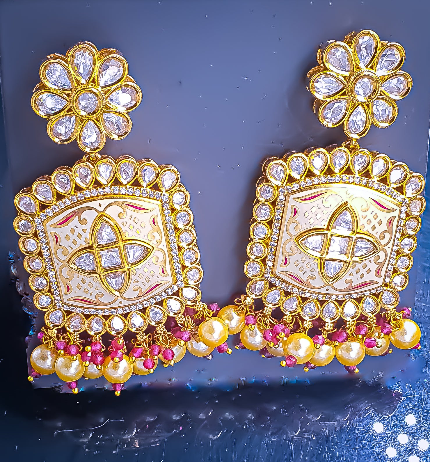 Introducing Raani's Ethnic Indian designer earrings with Kundan, pearls and cubic zirconia that are perfect for any special occasion. Aptly called Raani's Maya Earrings, these elegant earrings feature a gold-plated square design with intricate detailing, showcasing the beauty of traditional craftsmanship.