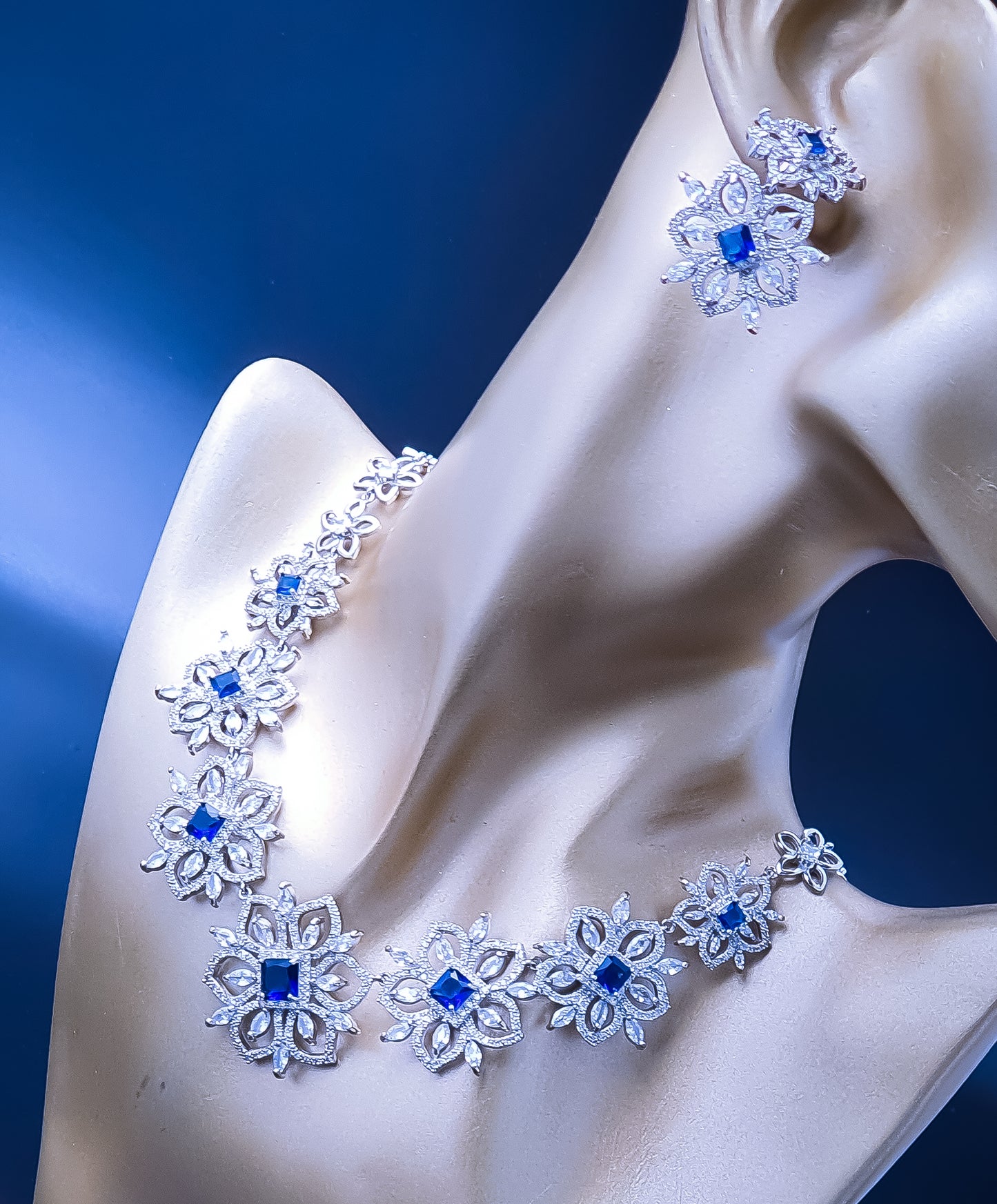 Titanium Steel Cubic Zirconia Necklace Set - Introducing Raani's Regal Blue Necklace Set, crafted with rhodium-finish Titanium Steel and Cubic Zirconia. This enchanting ensemble features a delicate floral design adorned with blue and white cubic zirconia that sparkle like stars in the night sky.