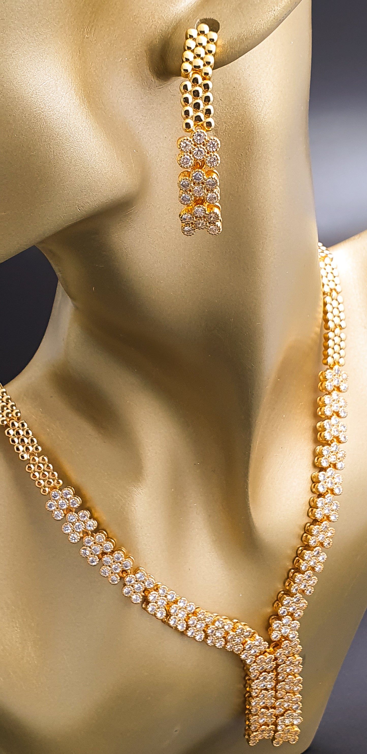 Introducing Raani's Golden Starlight Necklace Set, a rich gold plated designer necklace set that radiates enduring elegance. Crafted with high-quality gold plating and adorned with shimmering American Diamonds, this set dazzles with a celestial sparkle. Despite being artificial, the gold plating ensures lasting shine with proper care.