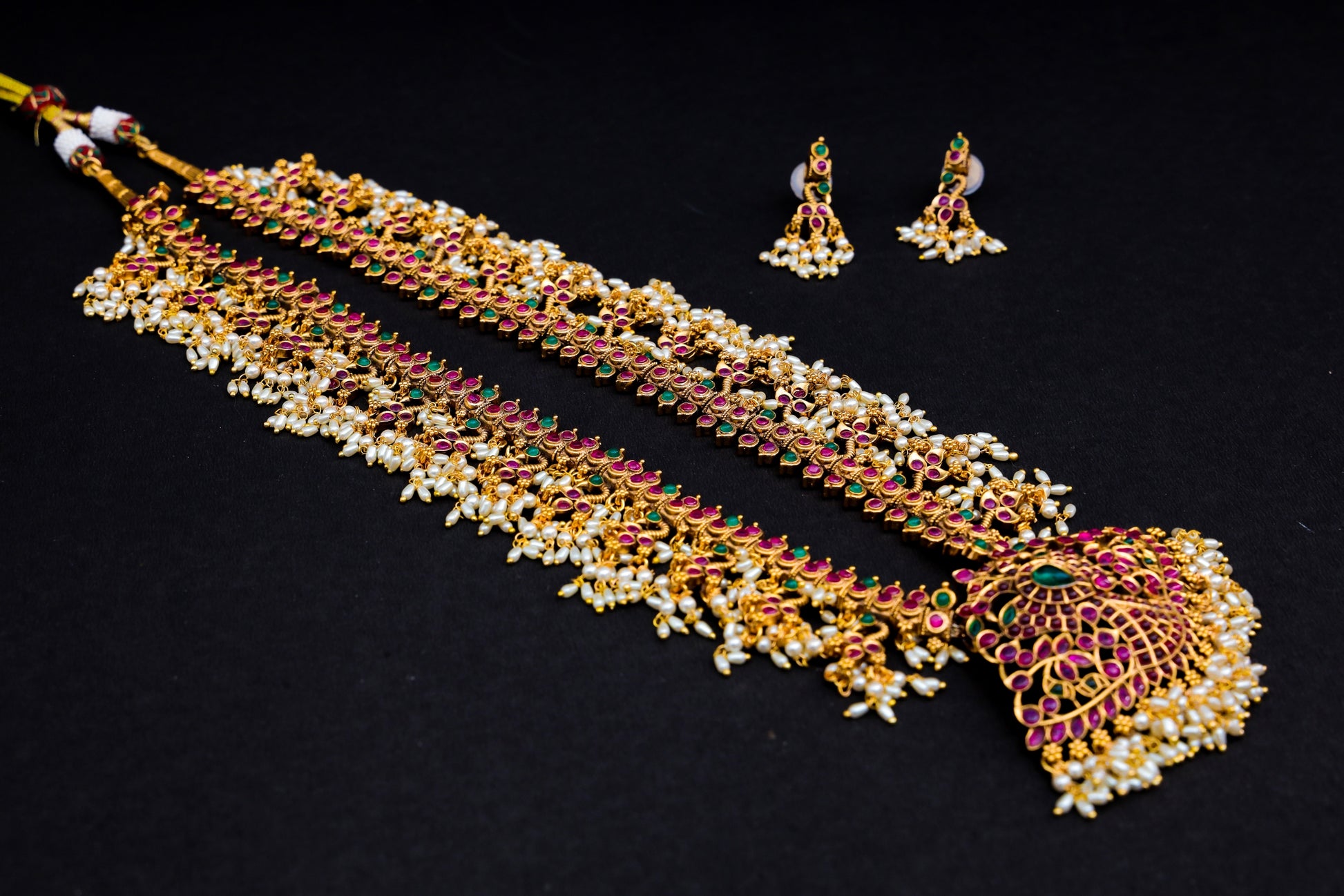 Introducing Raani's Hyderabadi Jadau Necklace Set, a rich gold plated Hyderabadi Jadau creation that embodies tradition and opulence. This exquisite set features delicate rice grain pearls and vibrant navratan stone work, meticulously arranged to capture the essence of Hyderabadi craftsmanship.