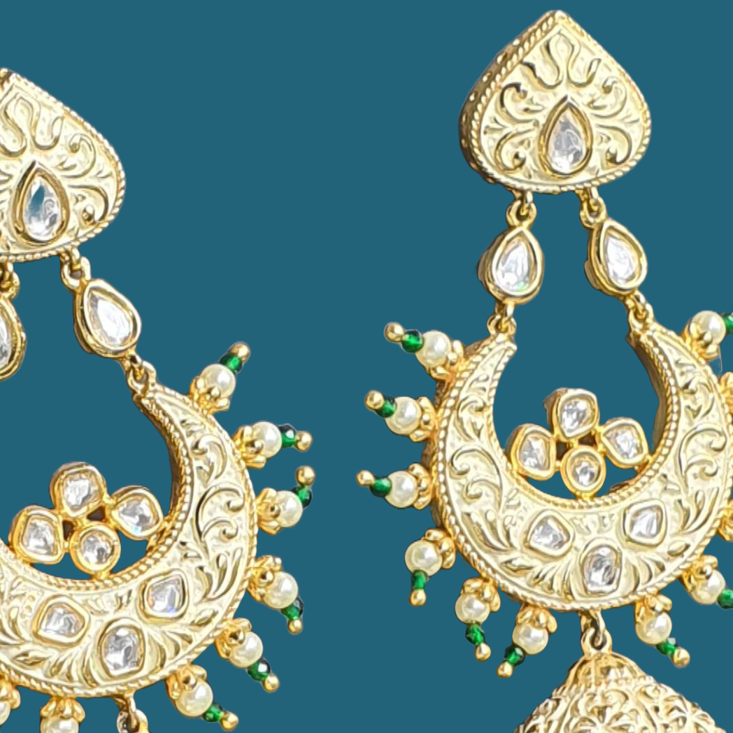 Raani's ivory colour Jodhpuri chandbali jhumkas with minakari and little pearls are a testament to exquisite Indian artistry. Gold-plated brass forms the intricate base, embellished with gleaming pearls and sparkling silver-foil kundan. The delicate golden minakari work on an ivory backdrop adds a touch of traditional colour, making these chandbali jhumka earrings a timeless treasure.