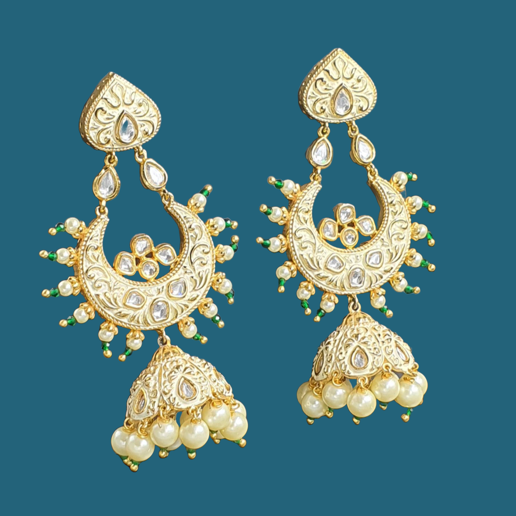 Raani's ivory colour Jodhpuri chandbali jhumkas with minakari and little pearls are a testament to exquisite Indian artistry. Gold-plated brass forms the intricate base, embellished with gleaming pearls and sparkling silver-foil kundan. The delicate golden minakari work on an ivory backdrop adds a touch of traditional colour, making these chandbali jhumka earrings a timeless treasure.